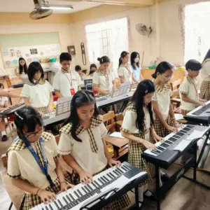 Students playing keyboards together in a classroom, practicing music as a group.